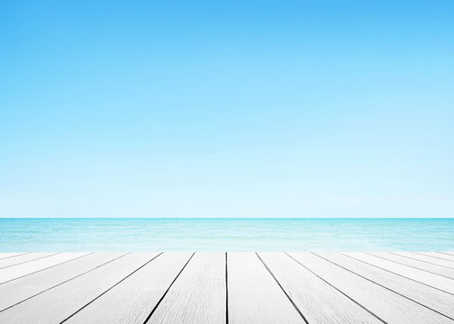 The blur cool sea background with wood floor foreground on horizon tropical sandy beach.	