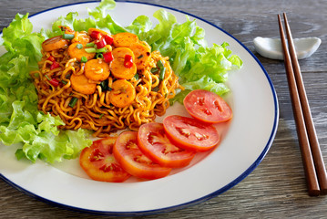 Stir fried spicy yellow noodle with sausage in white dish on gray wooden table