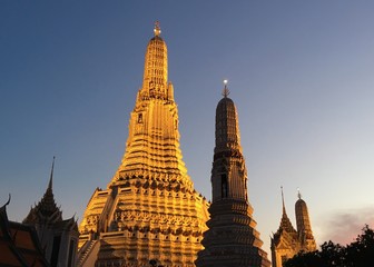 Naklejka premium Low angle view of golden pagoda at Wat Arun Ratchawararam temple shining in dark night.