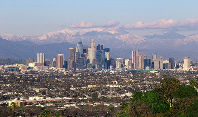 Panoramic view of the city of Los Angeles California with snowy mountain caps showing the end of the drought due to climate change.  The wide view shows Hollywood and Downtown.