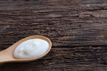 Natural homemade plain organic yogurt in wood spoon on wood texture background