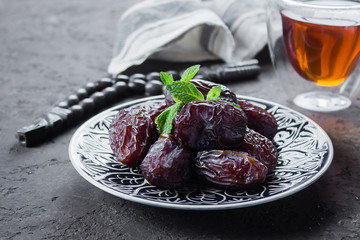 Ramadan kareem. Ramadan Food Concept. Fresh Dates and nuts with rosery on dark concrete background. . Top view. Copy space.