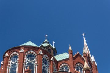 Fototapeta na wymiar Gothic Revival church with beautiful windows, dome, and spire against a blue sky, horizontal aspect