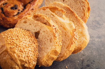 Close-up of Freshly baked bread on wooden table,Bakery Concept- gold rustic crusty loaves of bread and buns on black chalkboard background. 