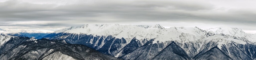 Fototapeta na wymiar Panoramic view of the Caucasus mountains covered by snow in the ski resort of Krasnaya Polyana, Russia.