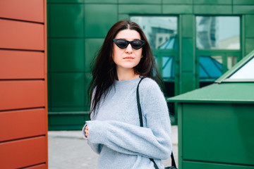 Urban style concept. Close up portrait of fashionable teenage girl in sunglasses posing on city street in summer. Glamour young woman wearing stylish clothes.