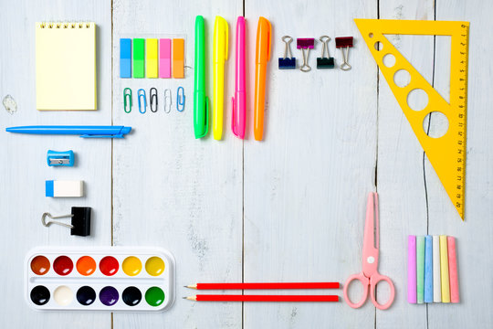 School supplies stationery, color pencils, paints, paper on pastel blue wooden table, back to school background concept with free copy space for text, modern elementary education. Kids desk top view.