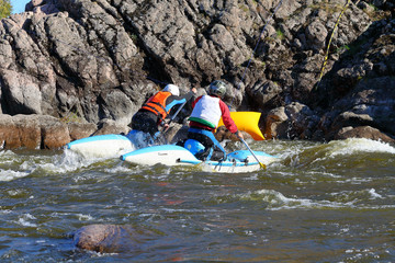 Two people on a catamaran pass the threshold of a mountain river. Rafting on rapids at whitewater...