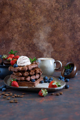 Chocolate and vanilla Belgian waffles with fresh berries on a ceramic plate on brown background. Sweet breakfast