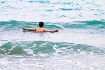 The young man is playing in the sea alone.