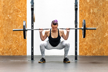 Young girl doing a back squat with a barbell