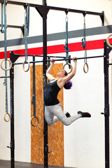 Fit young woman doing pull-ups on rings