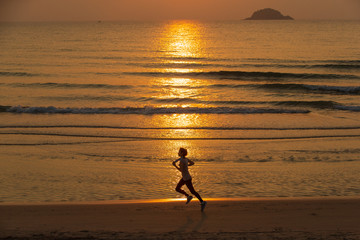 Woman running on beach at sunrise
