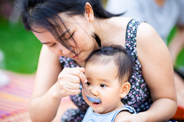 Asian woman feeding her baby girl by spoon