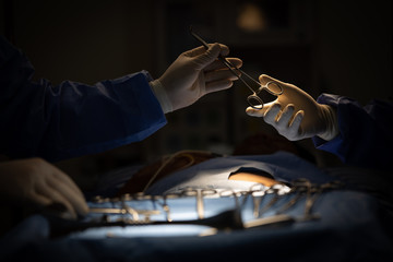 Doctors in sugery room sending medical device to other in operation