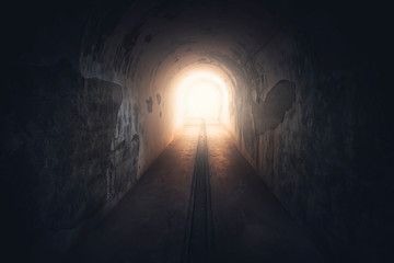 Light in end of tunnel. Long underground concrete corridor in abandoned bunker, toned - obrazy, fototapety, plakaty
