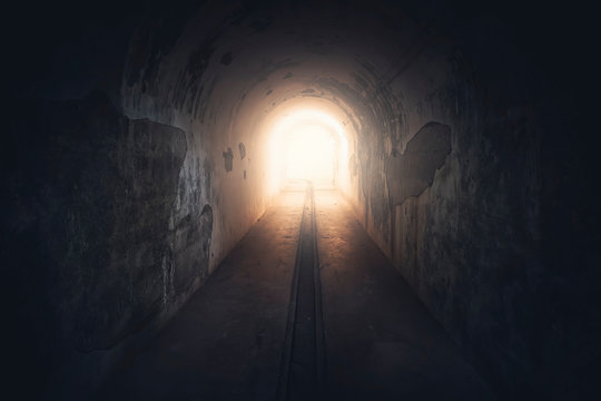 Fototapeta Light in end of tunnel. Long underground concrete corridor in abandoned bunker, toned