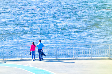 people walking along the promenade, Biking and scooters, watching the water flowing river or sea 