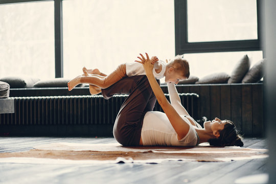 Pregnant Woman At Home. Mother With Son Doing Yoga. Family In A Room With Large Windows