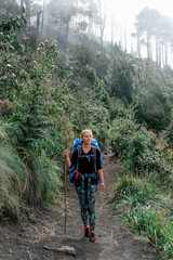 Obraz premium A young girl with a backpack on her back climbs a mountain volcano in Guatemala through a dead forest
