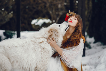 Woman in a winter forest. Lady with dog. Girl in a long white dress