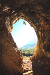 Rock climber climbs into the cave.