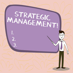 Conceptual hand writing showing Strategic Management. Concept meaning formulation and implementation of the major goals Confident Man in Tie, Eyeglasses and Stick Pointing to Board