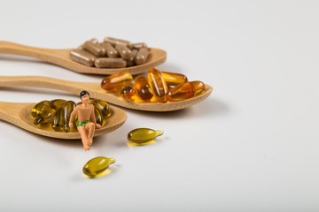 Fish oil capsules in a wooden spoon on white background, omega 3 and vitamin B,C,D healthy diet concept.