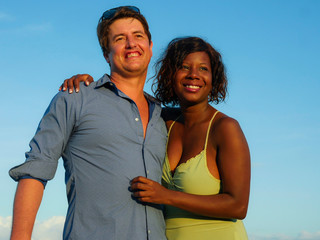 happy and beautiful mixed ethnicity couple with beautiful afro American woman and cheerful Caucasian man enjoying holidays honeymoon trip on beach cuddling sweet