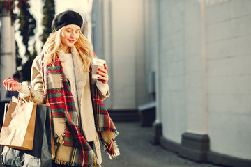 Elegant lady in a winter city. Stylish girl walking with shopping bags. Blonde in a cute beret