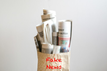 Fake news concept :  a paper bag filled with newspapers and the word Fake News on it
