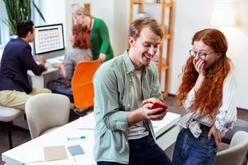 Joyful positive man showing a picture to his friend