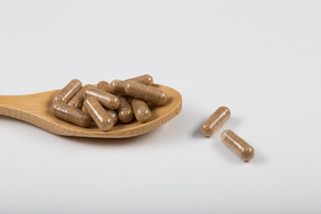 Fish oil capsules in a wooden spoon on white background, omega 3 and vitamin B,C,D healthy diet concept.