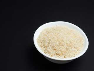 Basmati rice in a white bowl on a black background