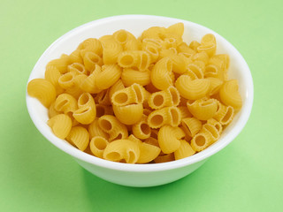 Macaroni in white bowl on a green background