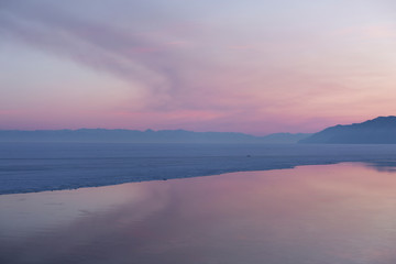 Beautiful sunset on frozen lake Baikal. Winter landscape.