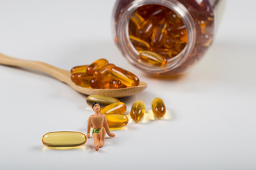 Fish oil capsules in a wooden spoon on white background, omega 3 and vitamin B,C,D healthy diet...