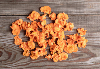 Pile of orange  carrot chips on old rustic wooden table.