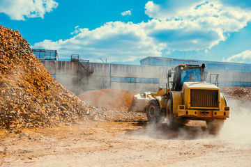 Brick factory equipment, large modern tractor moving bricks, excavator working