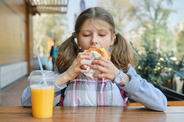 Portrait of girl student with backpack, eating burger with orange juice, background of outdoor fast food cafe