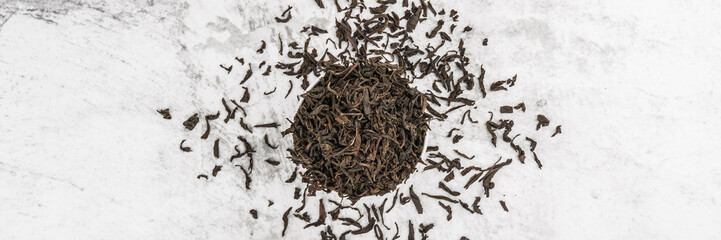 Dried tea is poured into a white ceramic cup on a marble table. View from above. Layout.