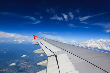 Wing of an airplane flying above in the morning clouds.