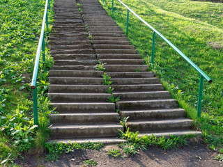 concrete staircase on a steep slope of green grass