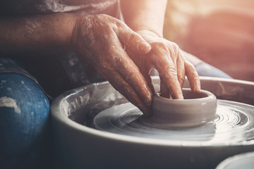 Master on potter wheel makes clay dishes. Workshop place