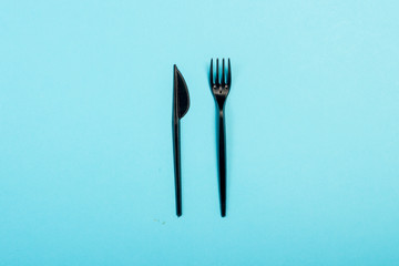 Black Disposable plastic tableware and appliances for food. Concept plastic, harmful, environmental pollution, stop plastic. Flat lay, top view.