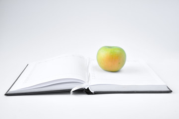 green apple on an open notebook