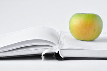 green apple on an open notebook