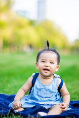 Little baby girl laughing sitting on grass field in the park