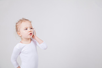 Portrait of the little girl's positive that talking on a cell phone, isolated on white background.