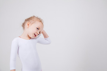 Portrait of the little girl's positive that talking on a cell phone, isolated on white background.